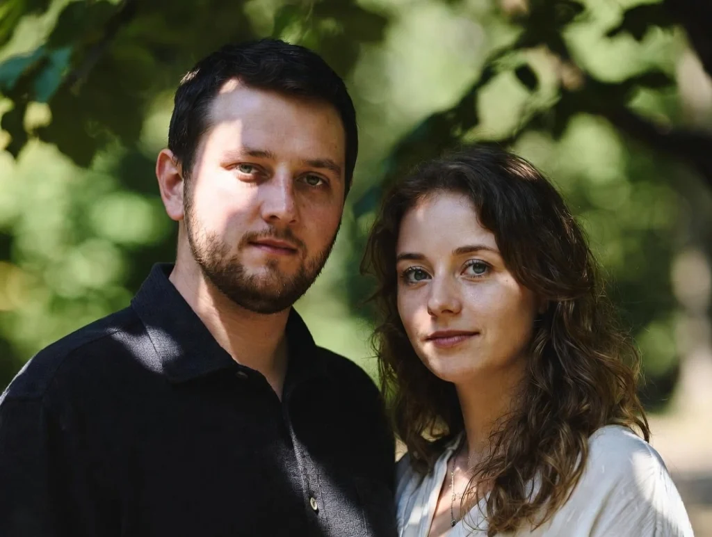 A leather notebook with a rose and a pen on a wooden desk in morning sunlight.